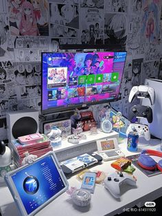 a desk with a large monitor, game controller and various items on top of it