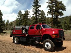 a large red truck parked on top of a dirt road