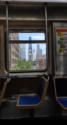 the inside of a subway car with city buildings in the back ground and windows on both sides