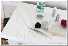 marble counter top with paint, brushes and other items sitting on it's surface