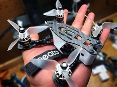 a hand holding a small silver and black model with propellers on it's palm