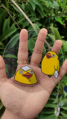 a hand holding a yellow rubber ducky sticker on it's palm