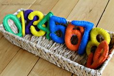 a basket filled with colorful felt letters sitting on top of a wooden floor