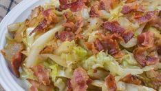 a white bowl filled with bacon and cabbage salad on top of a blue table cloth