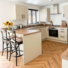 a kitchen with white cabinets and wooden floors has sunflowers on the counter top