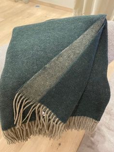 a green and grey blanket sitting on top of a wooden floor