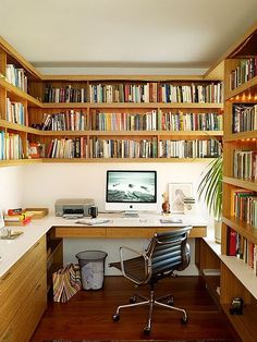 a home office with bookshelves full of books and a computer on the desk