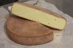 a piece of cheese sitting on top of a wooden cutting board