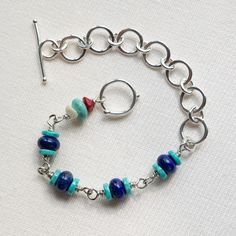 Looking for your new go-to piece? You've found it. Bright Lapis Lazuli sandwiched between slices of equally vivid Turquoise with a quirky contrasting link featuring Mother of Pearl, Coral and more Turquoise - Phew! All on a sinuous fine silver chain. Not for the shy retiring type, this luxurious bracelet will bring smiles every time it's worn, not to mention compliments on your great style. Each circle link is made by hand in fine silver which is a pure metal and will resist tarnish more than st Artisan Blue Bracelet As Gift, Artisan Blue Bracelet Perfect For Gift, Blue Stackable Bracelets As Gift, Artisan Blue Bracelet For Gift, Blue Stackable Bracelets For Gift, Artisan Blue Bracelet Gift, Nickel-free Blue Sterling Silver Bracelet As A Gift, Unique Blue Stackable Jewelry, Blue Bracelets With Unique Variations