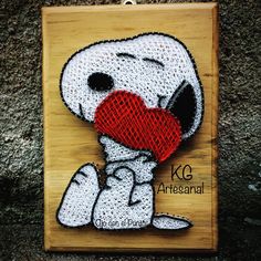 a wooden plaque with a cartoon dog holding a red heart in it's mouth