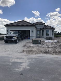 a black truck parked in front of a house under a blue sky with white clouds