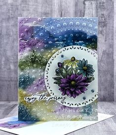 a close up of a card with water droplets on it and flowers in the middle