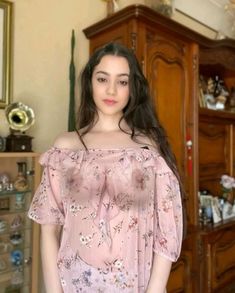 a young woman standing in front of a dresser with her hands on her hips and looking at the camera