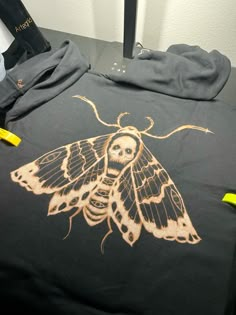 a black shirt with a moth on it