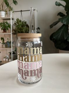 a glass jar with a straw in it sitting on a table next to a potted plant