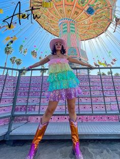 a woman standing in front of a carnival ride with her arms out and legs crossed