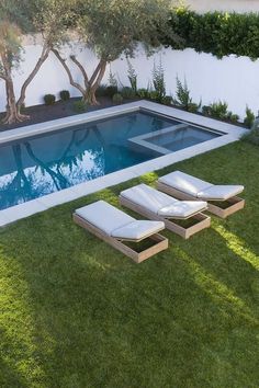 an empty swimming pool with lounge chairs in the grass