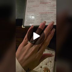 a woman's hand holding an item in front of a menu