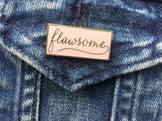 a pin with the word flossome on it sitting in a jean jacket pocket