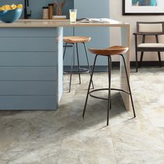 a kitchen with blue cabinets and stools next to a counter top in front of an island