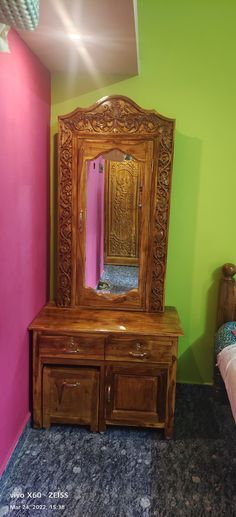 a wooden dresser and mirror in a room with pink walls, blue carpet and green wall