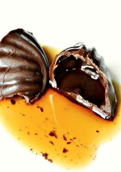 two pieces of chocolate covered in caramel sauce on a white surface, one half eaten