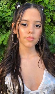 a girl with long hair and big hoop earrings on her head is looking at the camera