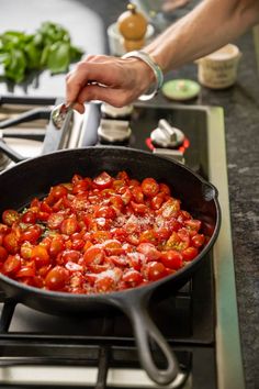 someone is cooking tomatoes in a skillet on the stove