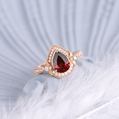 a close up of a ring with a red stone and diamonds on it's side