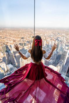 a woman standing on the edge of a tall building looking down at a cityscape