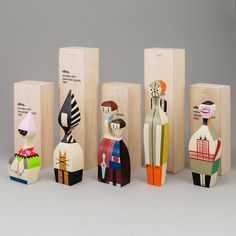 five wooden dolls are lined up in front of each other, with one sitting on the floor