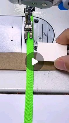 someone is using a sewing machine to sew on a green cord that has been stitched together