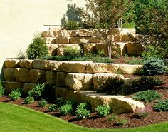 a stone wall and landscaping area in front of a house