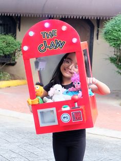 a woman is holding up a toy claw machine