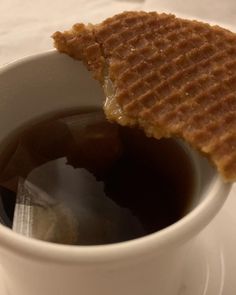 a waffle on top of a cup of coffee with syrup in the bottom and side