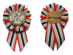 two red, white and black ribbons with an old photo on the top one has a pin