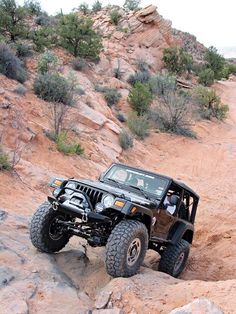 a black jeep driving down a rocky hill