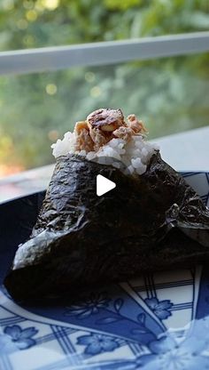 a blue plate topped with an eggplant covered in rice next to a window