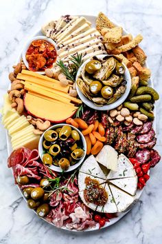 a platter filled with different types of cheeses, meats and olives