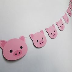 some pink pigs are hanging from a string on a white wall with other pig heads