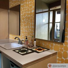 a kitchen with yellow and white wallpaper on the walls next to a sink in front of a window