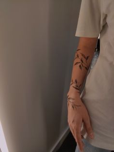 a person with a tattoo on their arm holding onto a wall next to a door