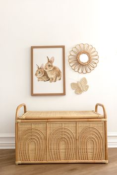 a rattan bench in front of a white wall with pictures on the wall above it