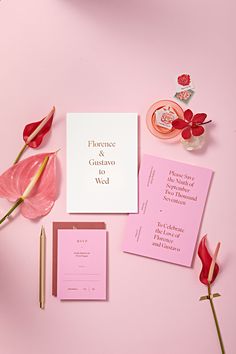 pink and white wedding stationery with calligraphy on it, flowers, and other items