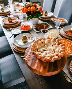 a wooden table topped with lots of plates and bowls filled with different types of food