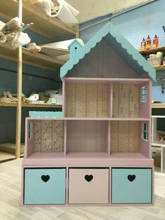 a pink and blue doll house with two drawers on the bottom shelf in front of it