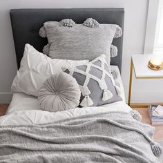 a bed topped with pillows and blankets next to a window