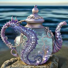 a glass teapot sitting on top of a rock next to the ocean