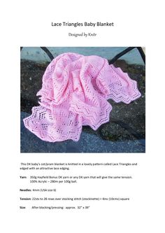 a pink knitted baby blanket sitting on top of a cement floor next to a black chair