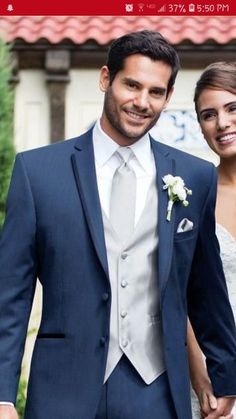 a man and woman dressed in formal wear standing next to each other smiling at the camera